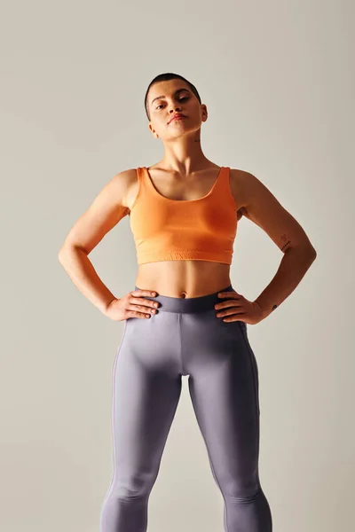 身材自信 留着短发 双手叉腰 灰色背景镜头 运动服 力量和健康等方面的曲线健身模型的女人 — 图库照片