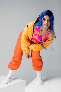 Tam boy, moda ve güzellik trendleri, gri arka planda mavi saçlı kadın, beyaz küplerin üzerinde duruyor, bireysellik, kentsel moda, canlı renk 