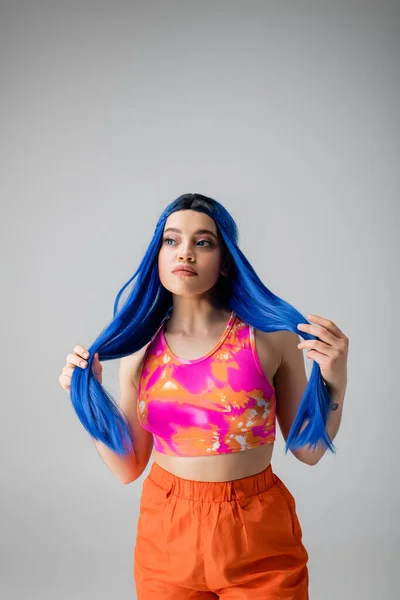 stock image youthful energy, tattooed young woman with blue hair posing in colorful clothes on grey background, individualism, modern style, urban fashion, vibrant color, fashion statement 
