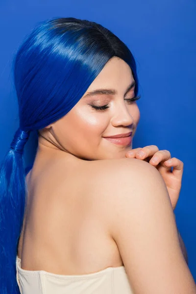 stock image glowing skin concept, portrait of happy young woman with vibrant hair color posing with bare shoulders on bright blue background, youth, individualism, beauty trends, unique identity 