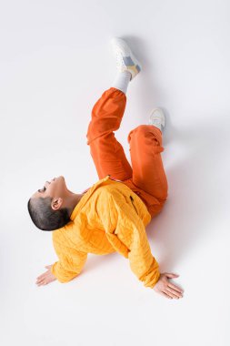 Üst tabaka, yaratıcı, moda anlayışı, gri arka planda oturan, gri elbiseli, şehir tarzı, bireysellik, enerjik ve gençlik enerjisi, şık görünümlü, dövmeli genç kadın. 