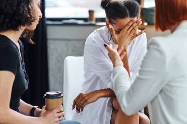 Depresyonda olan Afro-Amerikalı bir kadın elleri ile yüzünü gizliyor ve psikoloğun yanında ağlıyor ve kahve içen çok ırklı bir arkadaş danışma odasına gidiyor, problem çözme konsepti.