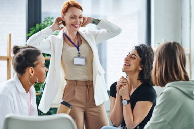 Memnun motivasyon koçu çeşitli çok kültürlü grupların yanında gülümsüyor ve psikoloji oturumu, anlayış, destek ve zihinsel sağlık konsepti sırasında gözleri kapalı gülen çok ırklı kadın.