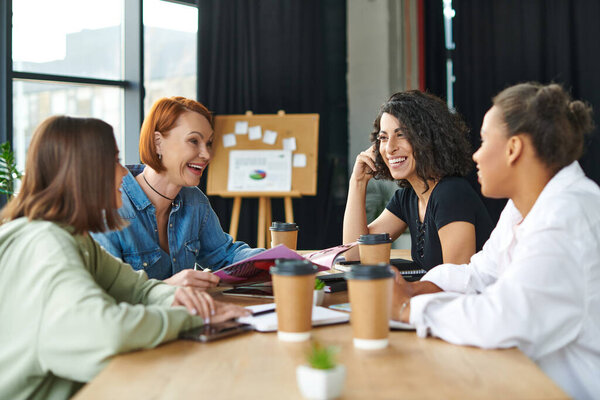 возбужденная рыжая женщина держит журнал и смеется возле еды на вынос напитки и разнообразные многокультурные девушки в клубе интересов, позитивное общение и обмен знаниями концепции