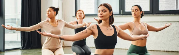 stock image diverse multicultural female friends in sportswear practicing yoga and meditating with closed eyes and outstretched hands, inner peace and body awareness concept, banner