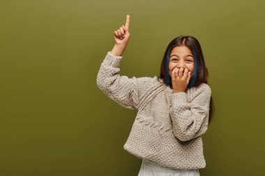 Gülen, boyalı saçları olan, örgü ören, parmağıyla işaret eden, yeşil renkli, modaya uygun ergen bir kız.