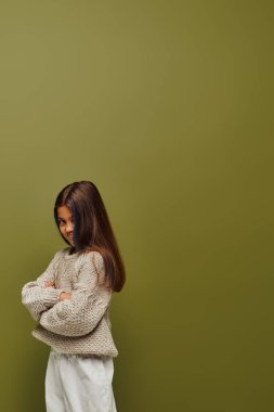 Rengarenk saçlı, renkli kazak giyen ve kollarını çapraz bağlayarak yeşil, modaya uygun, ileri görüşlü, izole edilmiş bir şekilde poz veren genç kız.