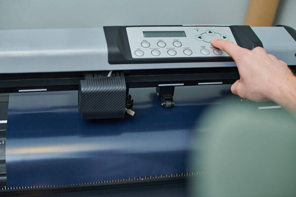 Cropped view of young artisan using screen printing machine while working in print studio, small business owner working on project, printmaking, creative process, workflow 