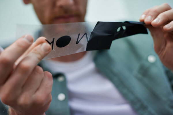 Cropped view of blurred young craftsman holding printing layer for silk screening in print studio, small business owner working on project, close up, creative process, workflow 