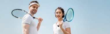 banner, happy couple in sportswear standing with tennis rackets on court, looking at camera, sport clipart