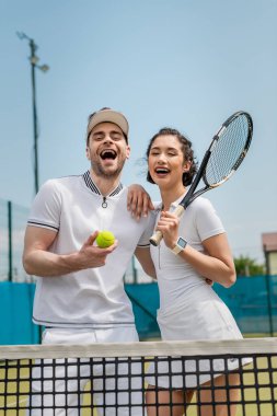 Tenis topu ve raket tutan heyecanlı adam ve mutlu kadın, yaz, çift sporu ve eğlence