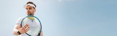 banner, handsome man in active wear and visor cap holding tennis racquet on court, sport and leisure clipart