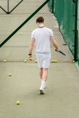Tenis raketli erkek oyuncu sahada topların etrafında yürüyor, hobi ve motivasyon, arka plan