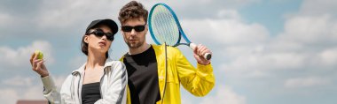 Pankart, hobi ve spor, güneş gözlüklü şık erkek ve kadın tenis kortunda raket ve top tutuyorlar.