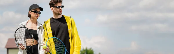 banner, summer sport, couple in sunglasses standing on tennis court with rackets, athletes fashion