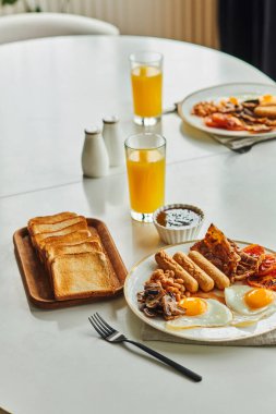 Geleneksel kahvaltıda evde kızarmış yumurta, sosis ve domuz pastırması ile portakal suyu ve reçel var.