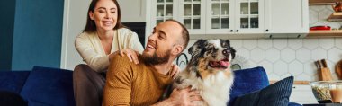 Gülümseyen kadın evde kahve ve patlamış mısırın yanında erkek arkadaşı ve sınır köpeğiyle vakit geçiriyor.