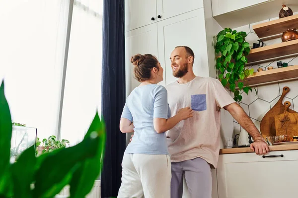 stock image Smiling bearded man in homewear talking to girlfriend and standing together in kitchen at home