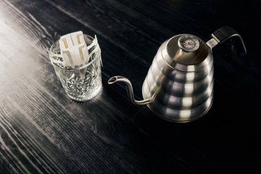 Dökme yöntemi, metalik su ısıtıcısı, siyah masanın üzerindeki filtre torbasında öğütülmüş kahve bardağı.