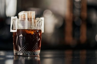 Kristal bardak, kağıt filtre poşette öğütülmüş kahve kafede siyah ahşap masa, espresso damlası metodu
