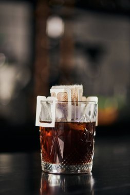 Siyah tezgahın üzerindeki kağıt filtre poşetinde öğütülmüş kahve, aromatik espresso, alternatif metot.