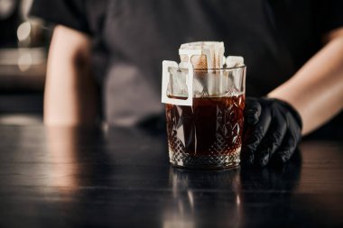 Kahve yapan baristanın kağıt filtre torbasında aromatik kahve ve siyah masada kristal cam karışımı manzarası.
