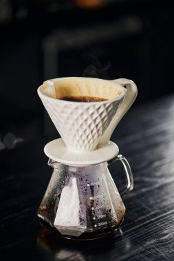Seramik damlatıcı, cam demliğin üzerine dökülen kahve siyah masada, alternatif V-60 tarzı. 