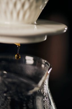 V-60 style espresso, close up view of pour-over coffee dripping from ceramic dripper into glass pot