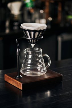 Serum tutacağı filtre torbasıyla, cam kahve demliği siyah ahşap tezgahta, alternatif V-60 tarzı metot