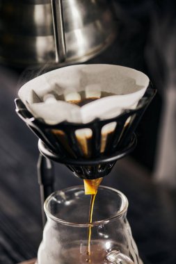 Damlama tezgahındaki kağıt filtreden cam kahve demliğine damlayan taze espresso, V-60 tarzı metot.