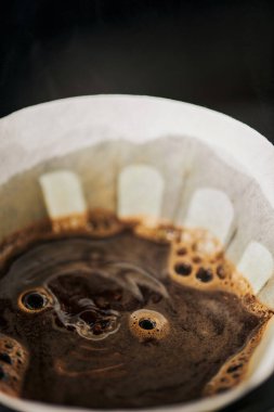 Kağıt filtre torbasında köpük bulunan taze aromatik kahvenin yakın görüntüsü, V-60 tarzı espresso.