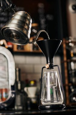 partial view of barista pouring boiling water into assembled siphon coffee maker in coffee shop clipart