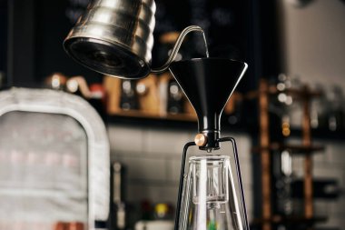 Dökümlü espresso hazırlığı sırasında su ısıtıcıdan sifon kahve makinesine kaynar su dökülüyor.