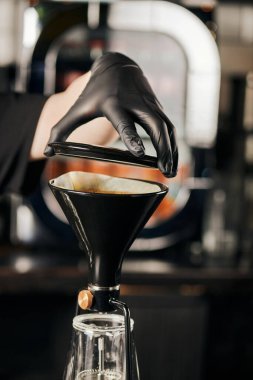 cropped view of barista in black glove preparing pour-over espresso and opening siphon coffee maker  clipart