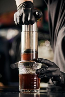 Siyah lateks eldivenli barista. Aero press 'te öğütülmüş kahve. Alternatif demleme yöntemi.