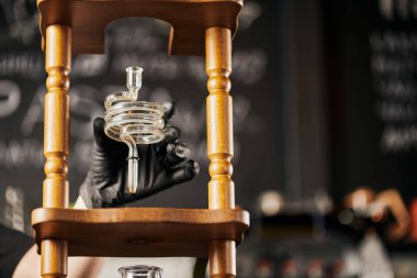 Siyah lateks eldivenli barista soğuk kahve makinesinin spiral kısmını tutuyor, alternatif yöntem.