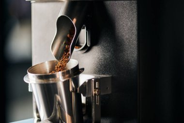 Kafe ekipmanları, elektrikli kahve öğütücüsünden metalik fincana dökülen kahve.