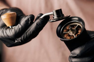 Barista 'nın elinde kahve değirmeni, kahve çekirdekleri, Arabika, içecek ve enerji tutarken kısmi görüntüsü 