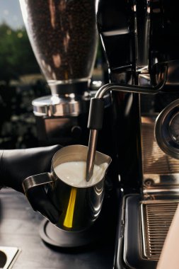 cropped view of barista foaming milk in pitcher, frothing milk, professional coffee machine, latte  clipart