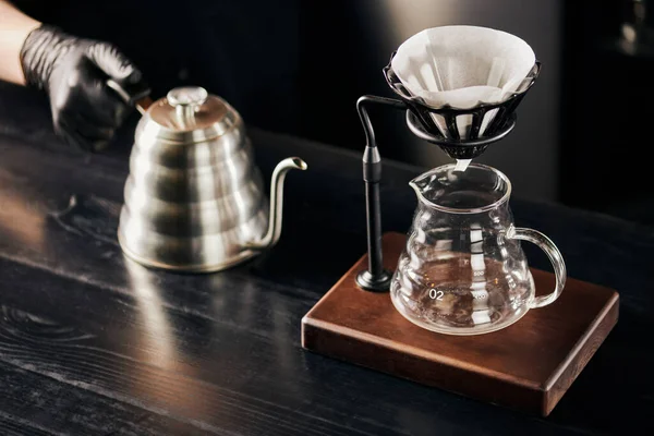 stock image V-60 style brewing, barista with drip kettle near dripper stand with coffee filter above glass pot