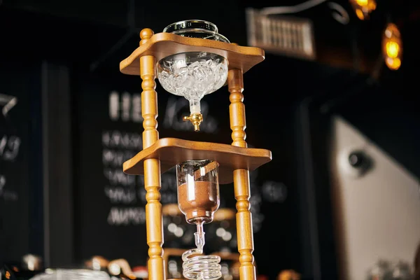 alternative espresso brew, low angle view of cold drip coffee maker with ice cubes and ground coffee