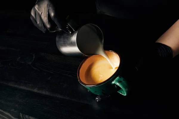 stock image barista holding pitcher, pouring milk, preparing cappuccino, aromatic espresso, latte art, cropped 