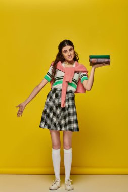 young student with books, brunette woman in checkered skirt posing on yellow backdrop, brunette clipart