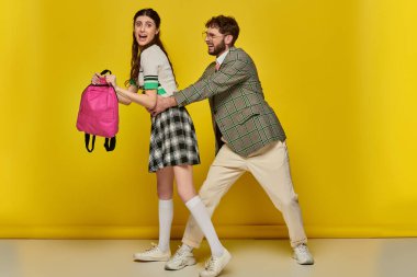 Komik öğrenciler, şakacı bir adam sarı arka planda bayan sınıf arkadaşının beline sarılıyor, üniversite hayatı.