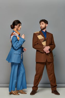 Özel dikim takım elbiseli şık erkek ve kadın, gri arka planda duruyorlar, moda çekimi, çift, mankenler.