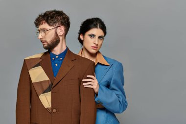 Moda çekimi, modaya uygun takım elbiseli çift, terziler, şık resmi kıyafetler, gri arka plan, modeller.