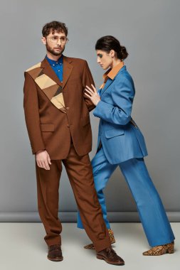 Moda pozu, gri arka planda resmi giyinmiş modeller, takım elbiseli kadın ve erkek, moda çekimi.