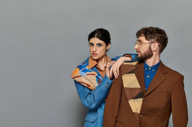 Gri arka planda poz veren şık kadın ve erkek, şık stil, resmi kıyafet,