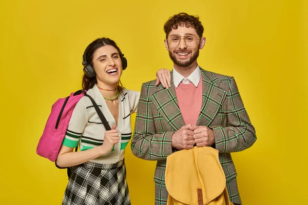 Telsiz kulaklıklı mutlu kadın sakallı adamın yanında duruyor, öğrenciler sırt çantası tutuyor, arka plan...