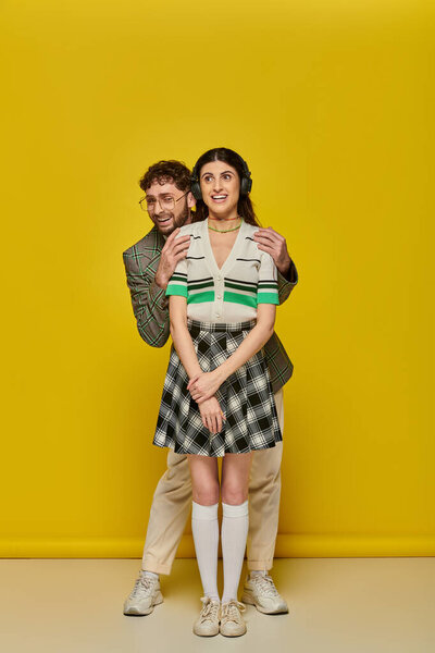 счастливая женщина в наушниках слушает музыку рядом бородатый мужчина, смешные студенты, желтый фон, колледж